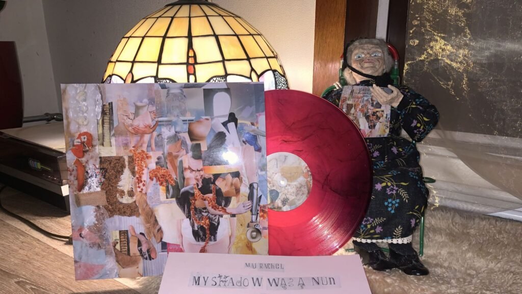 A vinyl record in front of a light and a nun doll