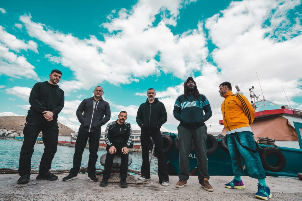 Band members of IOTA posing together outdoors during a sunny day