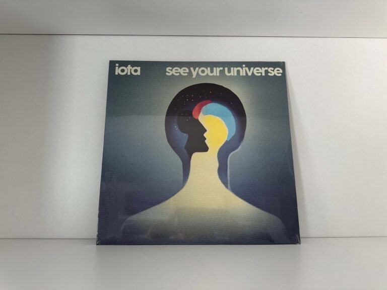 Physical copy of IOTA's album cover *See Your Universe* against a white wall.