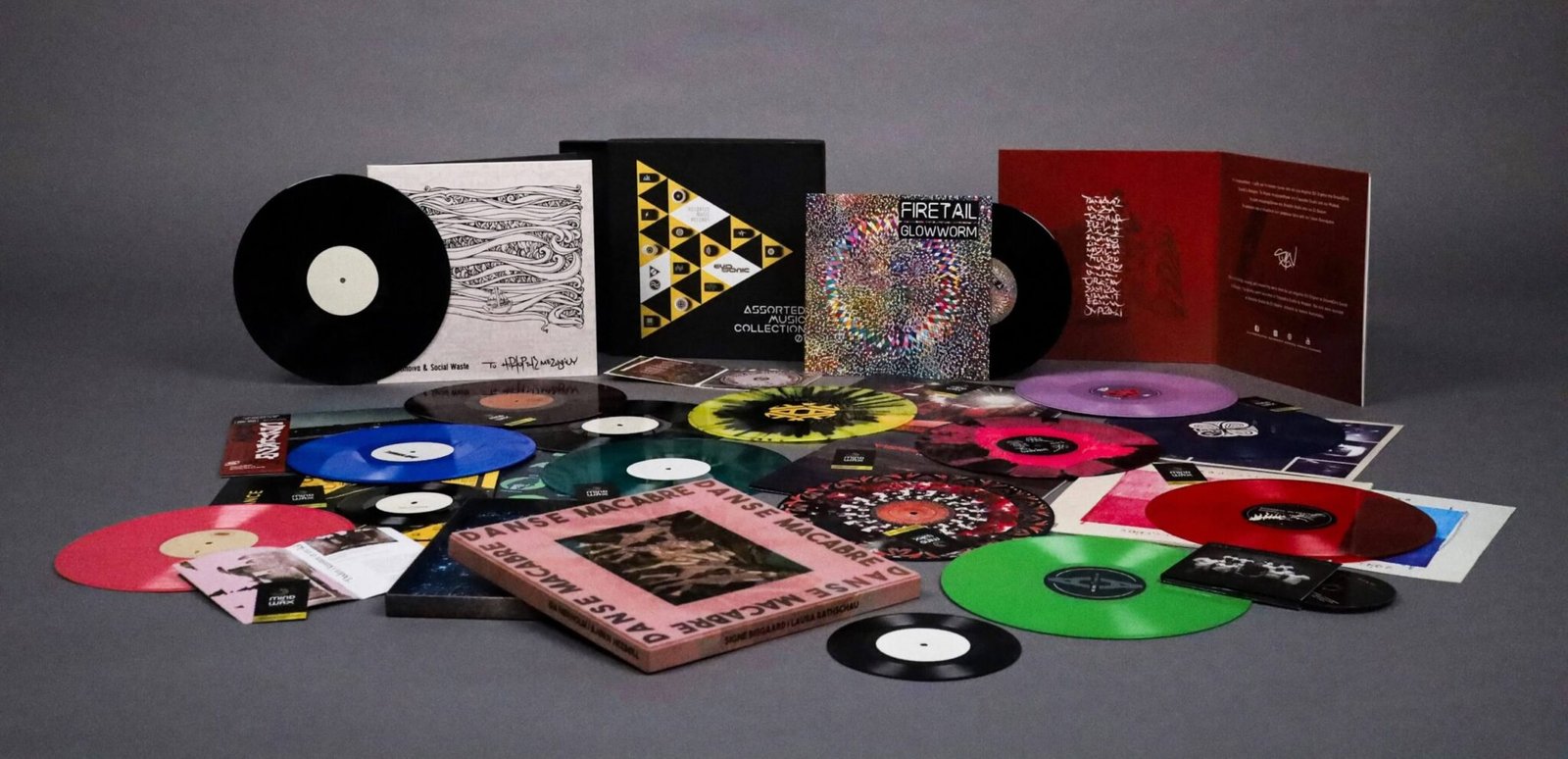 Vinyl records pressed by Mind The Wax displayed on the floor with packaging materials, box sets, and a wall backdrop.