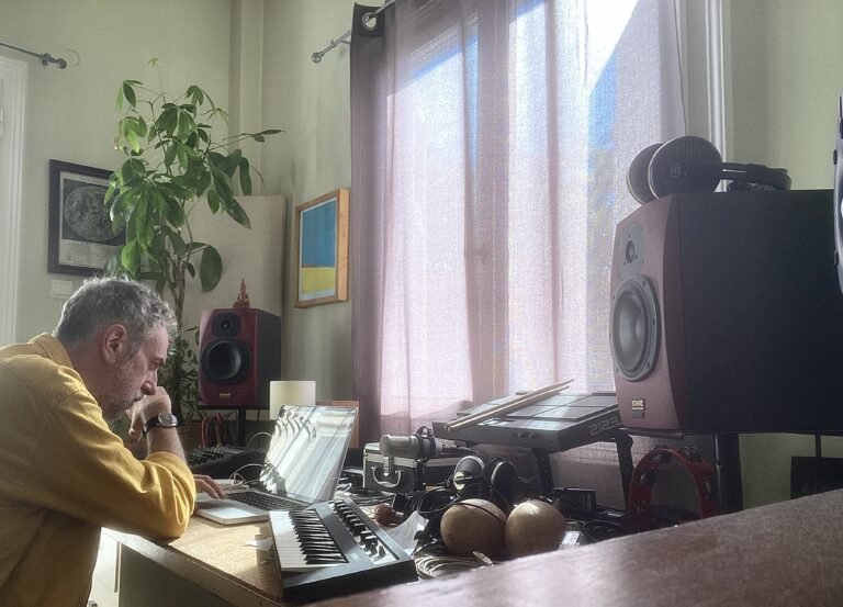 Blend Mishkin working in his music studio with a laptop, Yamaha Clavinova, and monitor speakers