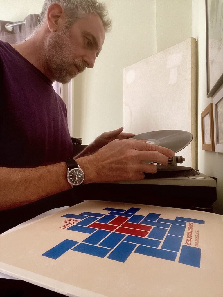 Blend Mishkin holding the Theory of Mind vinyl near a turntable with the album cover beside it