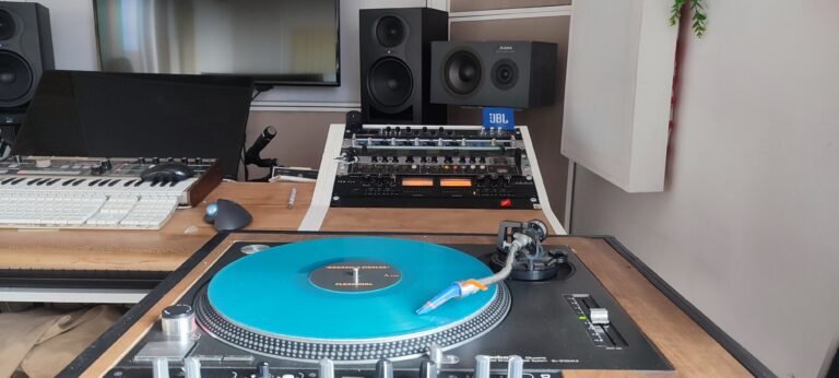 Turquoise vinyl on turntable with studio rack, speakers, synth keyboard, and microphone